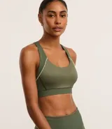 Top deportivo verde militar confeccionado en microfibra texturizada. Diseño con escote nadador en la espalda, copa y bies contrastante color amarillo.