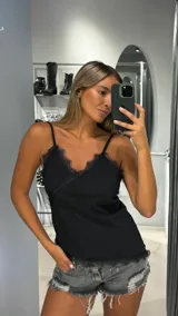 Top negro de tirantes finos con escote en V adornado con encaje negro.