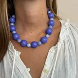 Collar corto de cuentas grandes color rojo brillante. Las cuentas son esféricas y de diferentes tamaños.