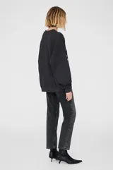 Buzo negro de cuello redondo, corte oversize y mangas largas. Estampado frontal con el nombre de la marca y la palabra 'California' en letras blancas estilo universitario.