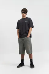 Remera negra de manga corta con corte oversize, cuello redondo y estampado pequeño en el pecho.