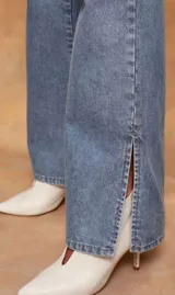 Pantalón de jean azul claro, corte bootcut, con bolsillos delanteros y traseros, y aberturas laterales en el ruedo.