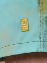 Short de baño color borgoña con estampado de hojas en tono sobre tono, cintura elástica con cordón ajustable y logo de la marca en la pierna.