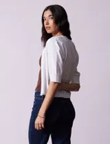 Bolero tejido blanco de manga corta con apliques de botones en los puños.