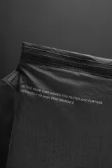 Bandolera negra de tejido técnico con correa ajustable, cierre con cremallera y detalle de texto y logo estampados.