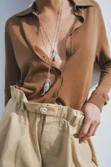 Chaqueta marrón de punto liso con cuello polo y manga larga. Cierre frontal con botones.