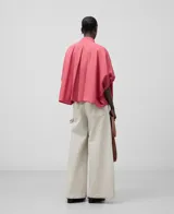 Camisa amplia de algodón color rosa, con cuello mao fruncido y bordado a tono. Manga corta con puño fruncido, botonadura frontal oculta con bordado a tono, bajo asimétrico y pliegue en la espalda.