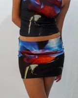 Conjunto de top musculosa y minifalda ajustada con estampado de rosa roja sobre fondo negro y azul.