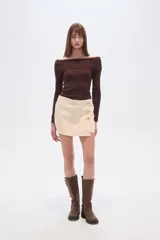 Short de jean color beige claro, tiro alto, corte ajustado y diseño cruzado con botones dorados decorativos en el lateral.