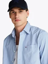 Camisa celeste de corte amplio confeccionada en sarga de puro algodón teñido en prenda, con cuello abotonado, bolsillo de parche en el pecho, puños redondeados con botón y logo de Tommy Hilfiger bordado en el bolsillo del pecho.