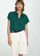 Camisa verde esmeralda de corte recto, con cuello camisero, mangas cortas y cierre frontal con botones.