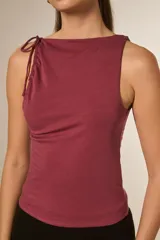 Top sin mangas de viscosa color negro, ajustado al cuerpo, con cuello redondo y frunces asimétricos en el hombro izquierdo.