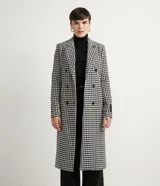 Campera alargada con cuello solapa, bolsillos y cierre de doble abotonado. Presenta un estampado cuadrillé pied-de-poule en blanco y negro, con un detalle contrastante en el puño. Confeccionada en polivelour, con forro de poliéster.