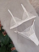 Conjunto de lencería color champagne, compuesto por un corpiño triangular de encaje con tirantes finos y una bombacha less de encaje con tiras ajustables.