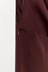 Vestido midi de tejido satinado color marrón oscuro (ciruela/vino), con escote drapeado (cowl neck) y tirantes finos. Presenta un panel tipo corsé con varillas y corchetes en la cintura, y una abertura lateral en la falda.