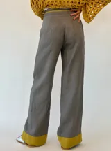 Pantalón gris de lino con corte palazzo y detalle de costuras amarillas en los laterales y en el ruedo.