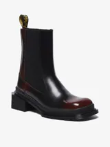 Bota Chelsea color bordó con puntera cuadrada, suela angular y tacón bajo. Presenta inserciones elásticas laterales y el clásico tirador de talón amarillo con el logo de la marca.