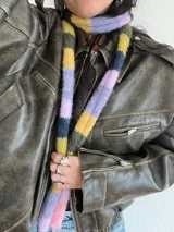 Bufanda angosta tejida a rayas horizontales en tonos rosa, lila, amarillo, verde y azul marino.