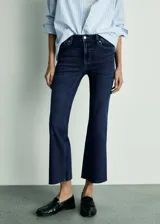 Jeans de tiro alto color azul oscuro, corte cropped y acampanado, con cinco bolsillos y cierre de cremallera y botón.