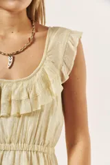 Vestido corto color crema con textura brillante, escote redondo con volados y cintura elastizada.