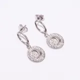 Par de aros colgantes plateados, compuestos por un aro ovalado superior del que cuelga un dije circular texturizado con una media luna en relieve.