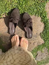 Mocasines tipo mule color beige, con detalle de cordones y ojales metálicos.