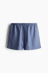 Short azul de lino y viscosa, corte holgado, cintura elástica con cordón, bolsillos laterales y aberturas cortas en los bajos.