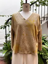 Remera de manga larga color beige con estampado botánico verde y amarillo, escote en V, corte ajustado y tajos laterales.