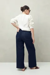 Pantalón de jean azul oscuro, de corte ancho y tiro alto, con bolsillos delanteros cuadrados y amplios.