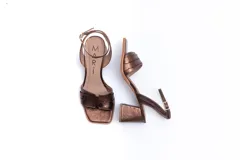 Sandalias de cuero color bronce con textura tipo cocodrilo, con tira delantera ancha y tira fina con hebilla al tobillo. El tacón es ancho y cuadrado.
