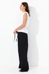 Pantalón negro de corte holgado en algodón, con tiro alto, cintura elástica fruncida y cordón para ajustar. Piernas anchas con bolsillos laterales.