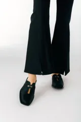 Zuecos negros de cuero con detalle metálico plateado en la tira superior.