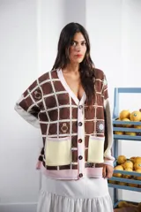 Cardigan oversized de tejido jacquard color crema con diseño de cuadrados en marrón y detalles bordados. Tiene cuello en V, cierre con botones, mangas largas y bolsillos frontales.