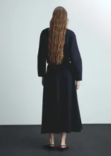 Falda midi evasé color azul marino, de tejido fluido con detalle de pinzas y dos bolsillos laterales.
