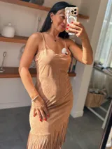 Vestido color beige con breteles finos, corte ajustado y falda con flecos.