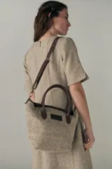 Cartera tipo tote de lana color beige con forro, cierre y asa de cuero regulable.