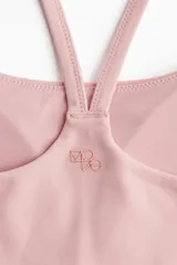 Top deportivo color rosa con breteles finos cruzados en la espalda y copas removibles.