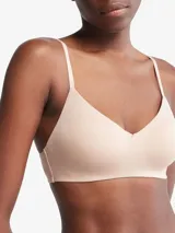 Corpiño Calvin Klein color piel, ligeramente forrado, sin aros, con breteles finos con logo de la marca y escote en V.