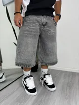 Bermuda de jean gris oscuro con lavado ácido, corte ancho y largo tipo culotte. Presenta bordados de strass blancos en forma de líneas curvas en la parte superior y un denso aplique de strass en el ruedo.