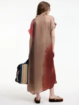 Vestido camisero largo con botones frontales, manga corta, cuello mao y bolsillos laterales ocultos. Estampado con efecto tie-dye en tonos marrones y rosados.