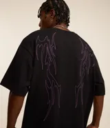 Remera negra de corte oversized, confeccionada en tejido de malla de algodón sostenible. Presenta cuello redondo, mangas cortas y estampa tribal con lettering en el frente.