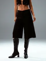 Pantalón culotte negro de vestir, con tiro alto, corte ancho y largo a la pantorrilla.