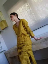 Vestido corto color rojo de lino con cuello en V y mangas 3/4. Presenta cierre frontal con botones y jareta ajustable en la falda. El largo es regulable.