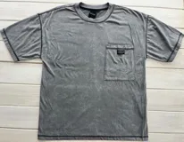 Remera gris con efecto gastado, cuello redondo, bolsillo en el pecho y costuras reforzadas.