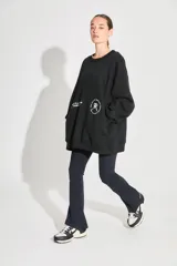 Buzo oversize negro de frisa con cuello redondo, hombros caídos, bolsillos delanteros y estampa serigráfica en delantero y espalda.