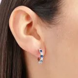 Aros tipo argolla plateados con incrustaciones de circonitas azules y blancas.