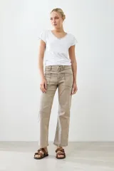 Pantalón de jean color beige, de corte recto, con bolsillos laterales y traseros. Se ajusta a la cintura con cinturón de cuero marrón.