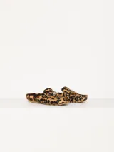 Mocasín de cuero vacuno con estampado animal print, detalle metálico en forma de corazón y suela de goma.