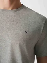 Pijama gris compuesto por una remera de manga corta con cuello redondo y un pantalón largo. La remera tiene un pequeño bordado en el pecho.