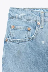 Pantalón de jean celeste claro, corte baggy, tiro medio, largo hasta el tobillo y con roturas grandes en ambas piernas.